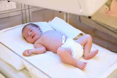 Newborn child under ultraviolet lamps in hospital