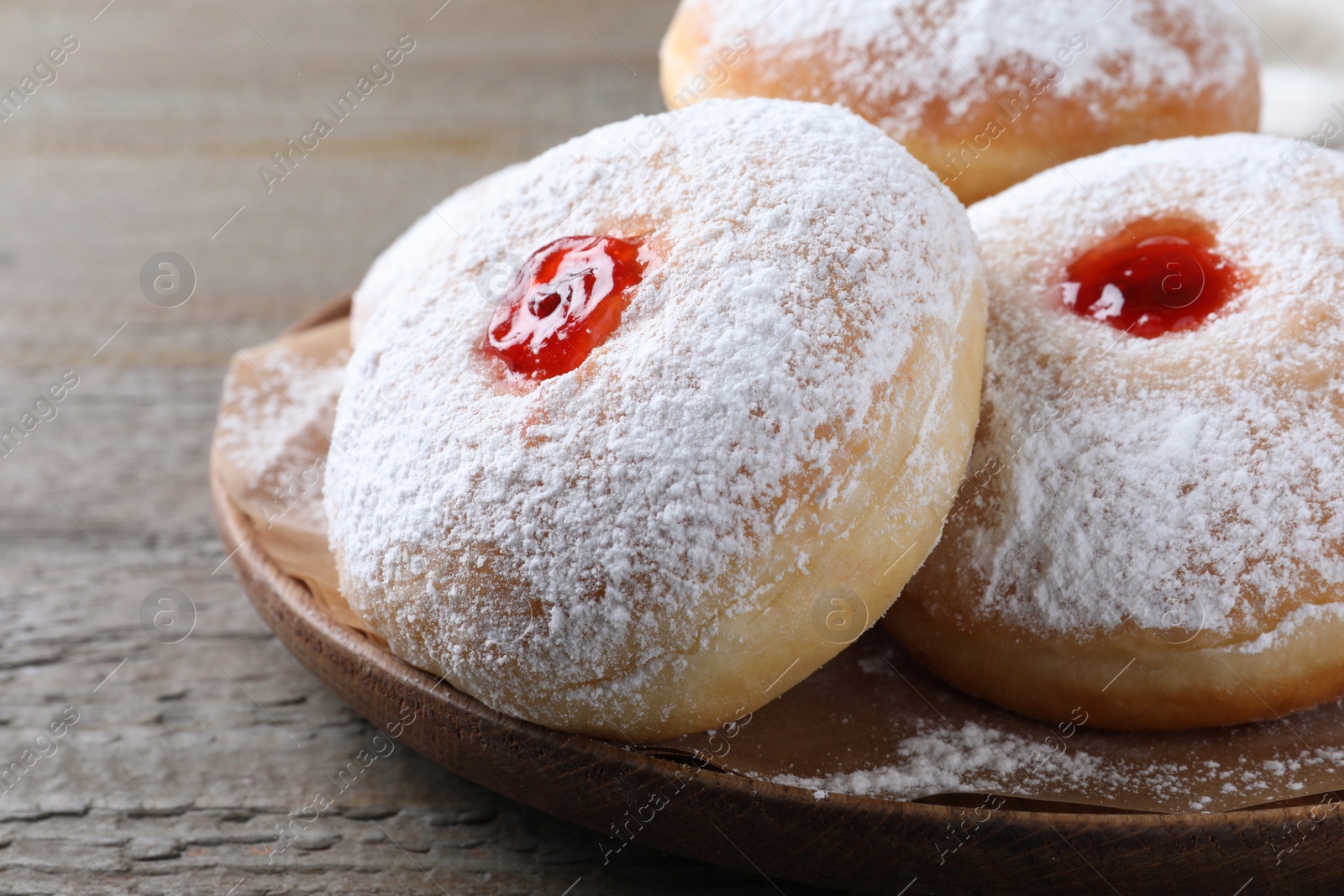 Photo of Delicious donuts with jelly and powdered sugar on wooden table, closeup