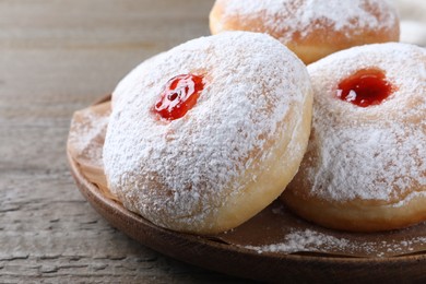 Delicious donuts with jelly and powdered sugar on wooden table, closeup