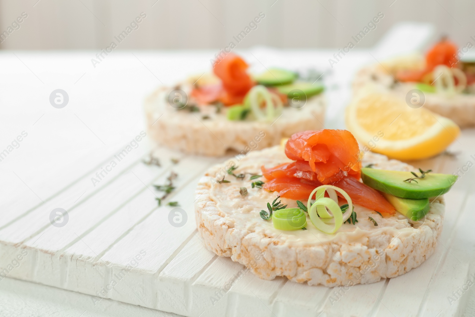 Photo of Crispbreads with fresh sliced salmon fillet and avocado on wooden board, closeup