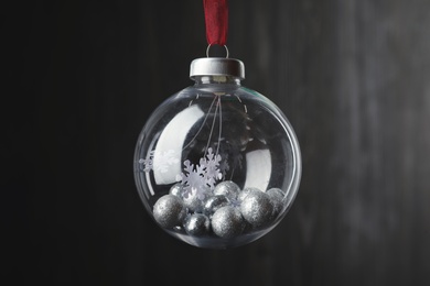 Photo of Beautiful Christmas snow globe hanging on blurred background