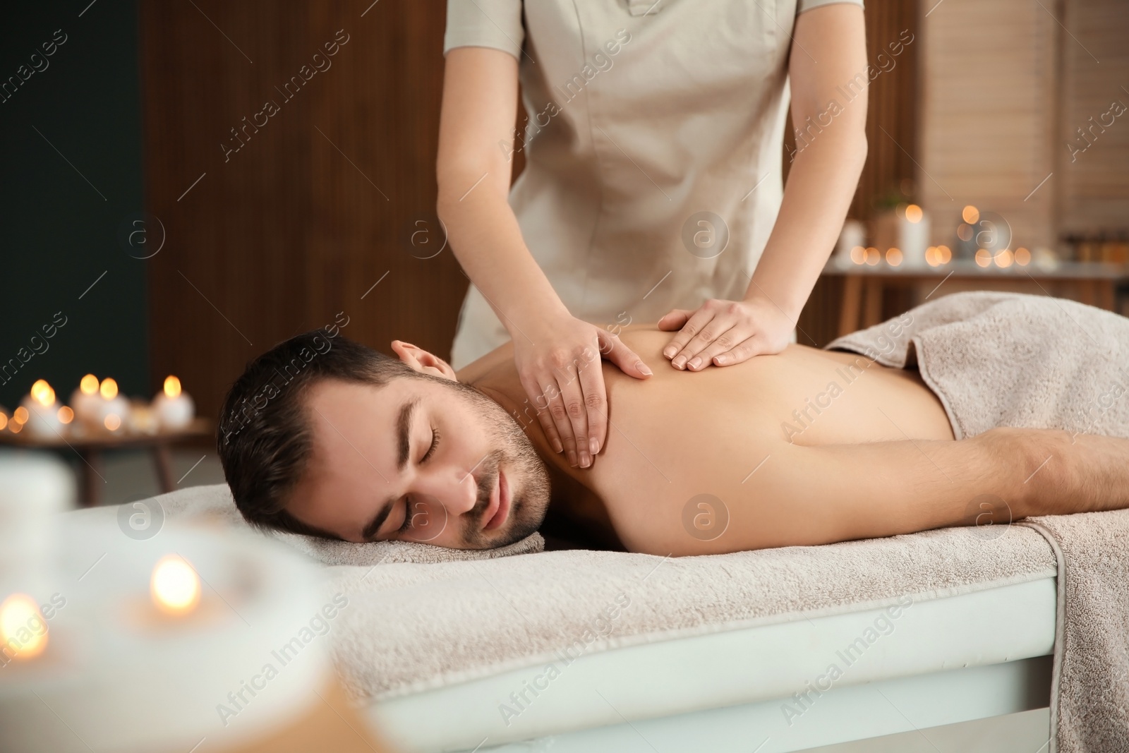 Photo of Handsome man receiving back massage in spa salon