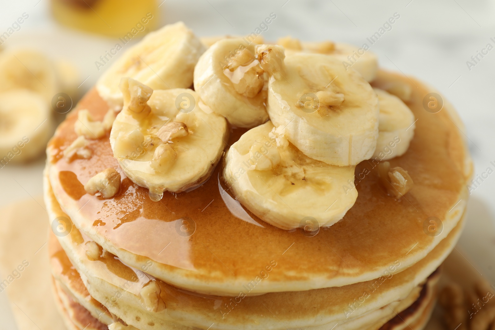 Photo of Delicious pancakes with bananas, walnuts and honey on table, closeup