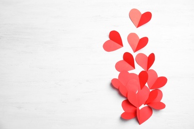 Photo of Small paper hearts on wooden background, top view