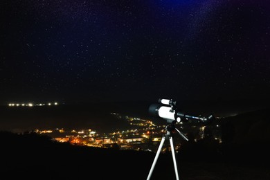 Photo of Picturesque view of city and modern telescope in night outdoors. Learning astronomy