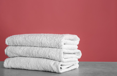 Photo of Stack of fresh towels on light grey stone table