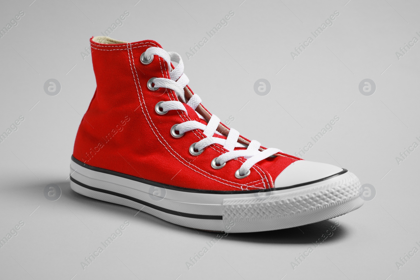 Photo of One new stylish red sneaker on light grey background