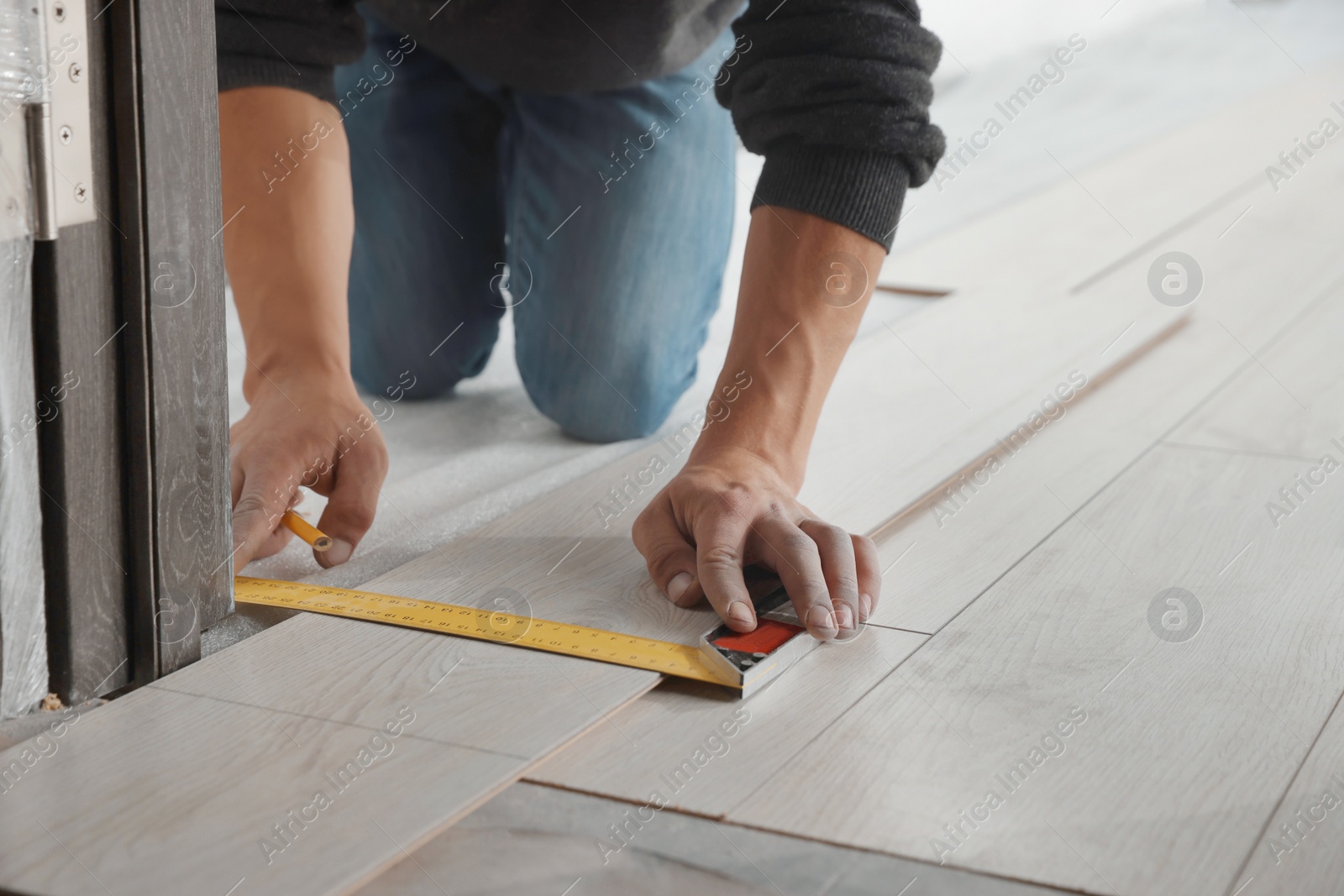 Photo of Worker installing new laminate flooring in room, closeup