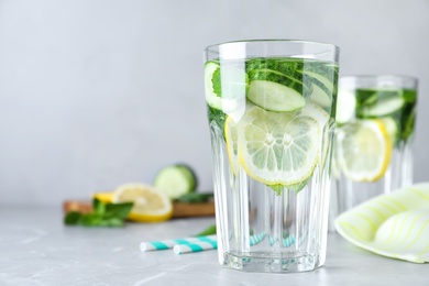 Photo of Refreshing water with cucumber, lemon and mint on light grey table, closeup