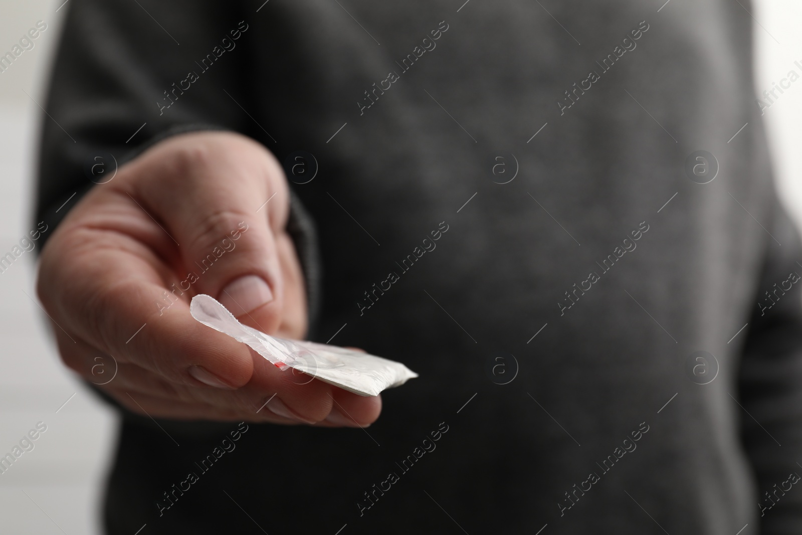 Photo of Drug addiction. Man with plastic bag of cocaine on light background, closeup