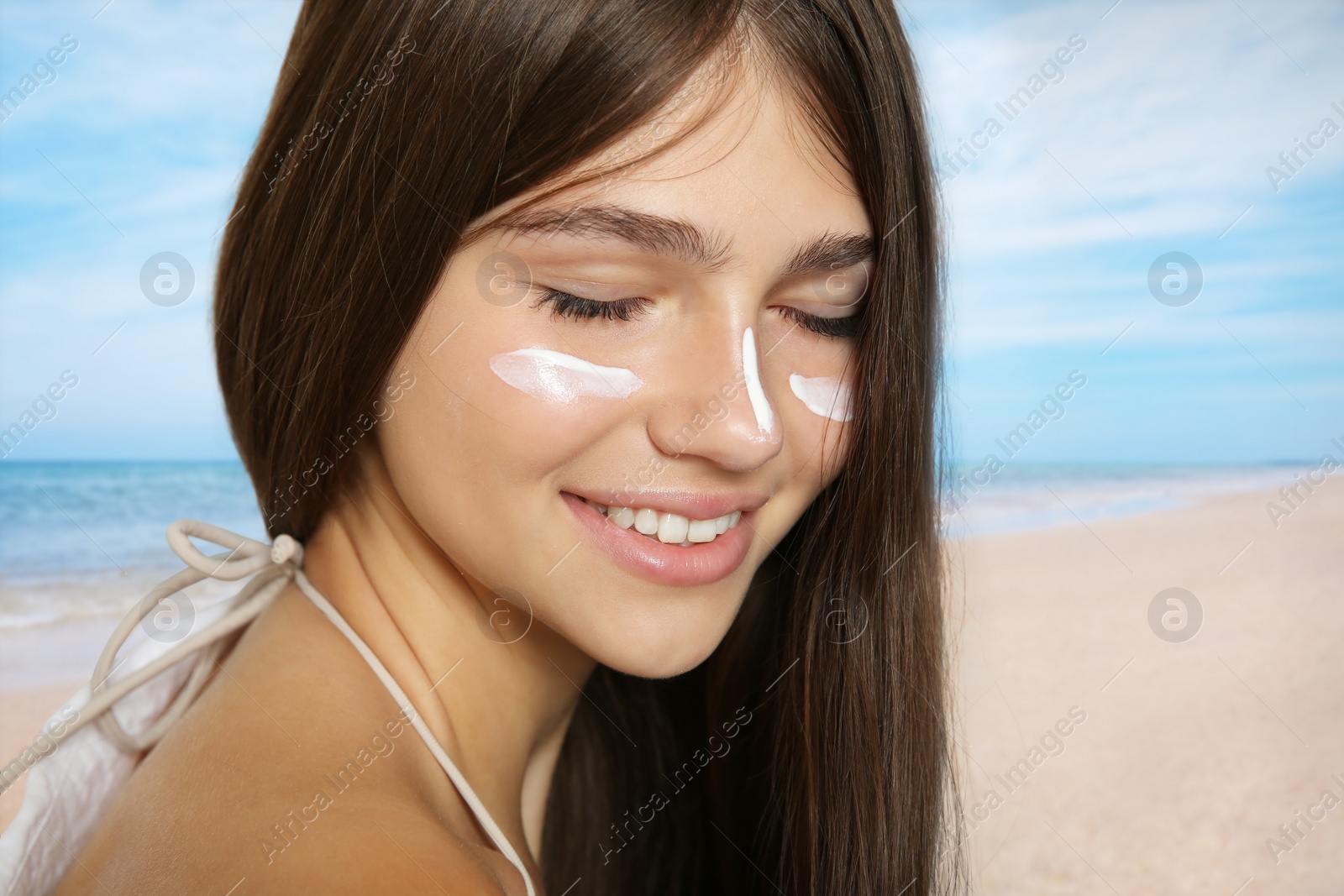 Image of Teenage girl with sun protection cream on her face near sea, closeup