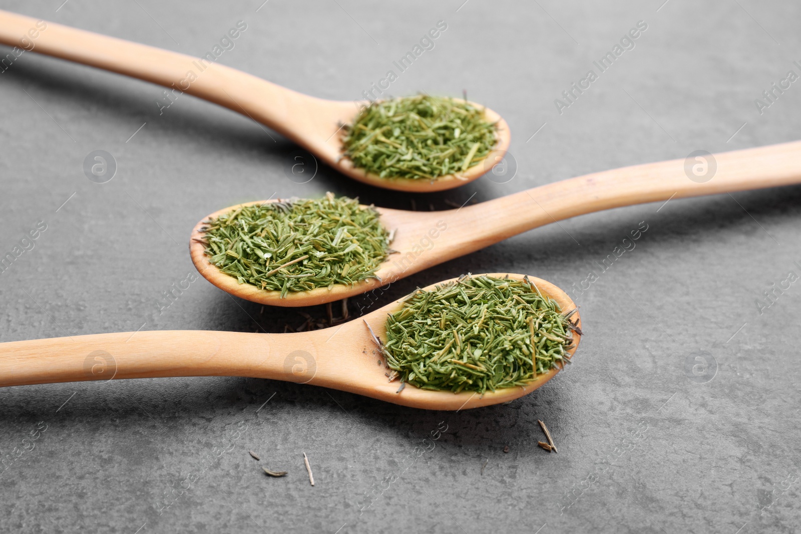 Photo of Spoons with dried thyme on grey table, closeup