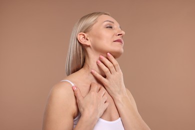 Beautiful woman touching her neck on beige background