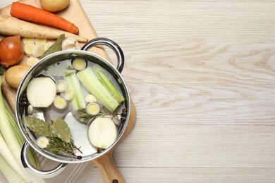 Pot and different ingredients for cooking tasty bouillon on white wooden table, flat lay. Space for text