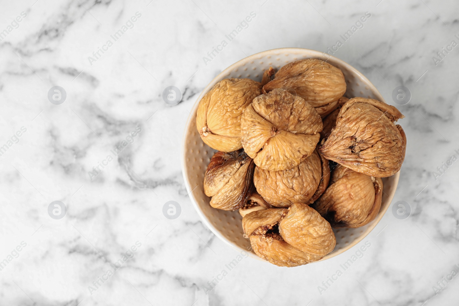 Photo of Bowl of tasty dried figs on marble table, top view. Space for text
