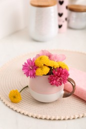 Photo of Beautiful bright flowers in cup on table