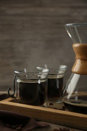 Photo of Glass chemex coffeemaker with coffee and beans on wooden table