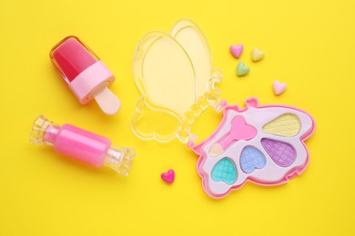 Photo of Decorative cosmetics for kids. Eye shadow palette and lip glosses on yellow background, flat lay
