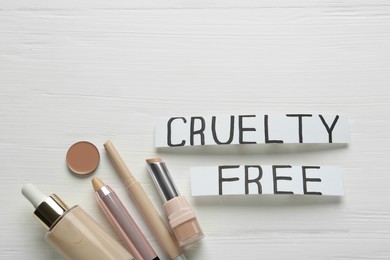 Photo of Flat lay composition with words Cruelty Free and different cosmetic products not tested on animals against white wooden background