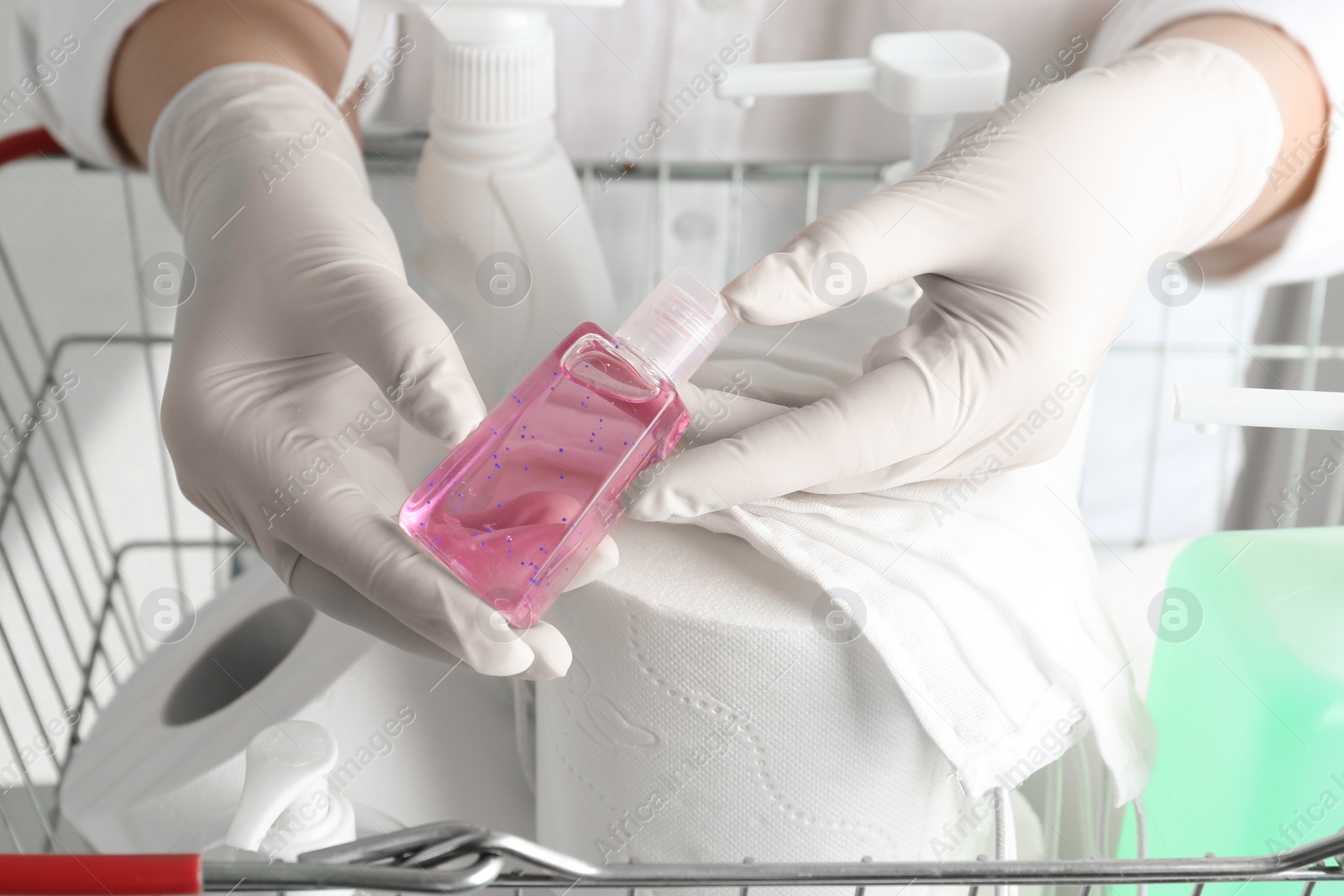 Photo of Woman with shopping basket full of antiseptics and toilet paper, closeup. Panic caused by virus