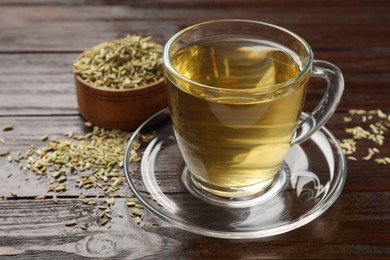 Photo of Aromatic fennel tea and seeds on wooden table, closeup. Space for text