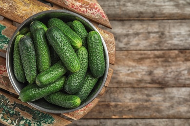 Photo of Bowl with ripe fresh cucumbers on table, top view