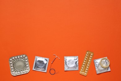 Contraceptive pills, condoms and intrauterine device on orange background, flat lay with space for text. Different birth control methods