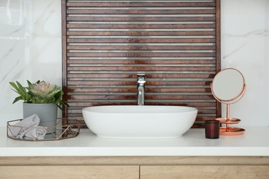 Bathroom counter with stylish vessel sink and small mirror. Interior design