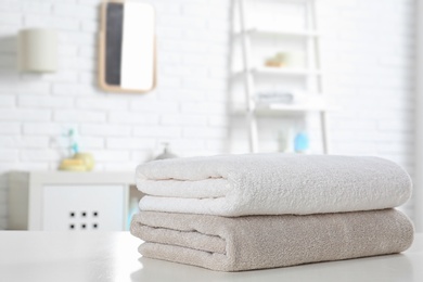 Photo of Stack of fresh towels on table in bathroom. Space for text