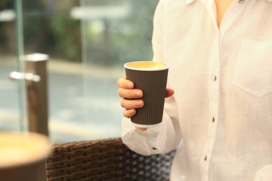 Photo of Woman holding takeaway paper cup outdoors, closeup and space for text. Coffee to go