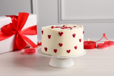 Photo of Bento cake, candles and gift box on white wooden table. St. Valentine's day surprise