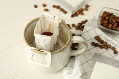 Photo of Drip coffee bag in cup on white table, closeup