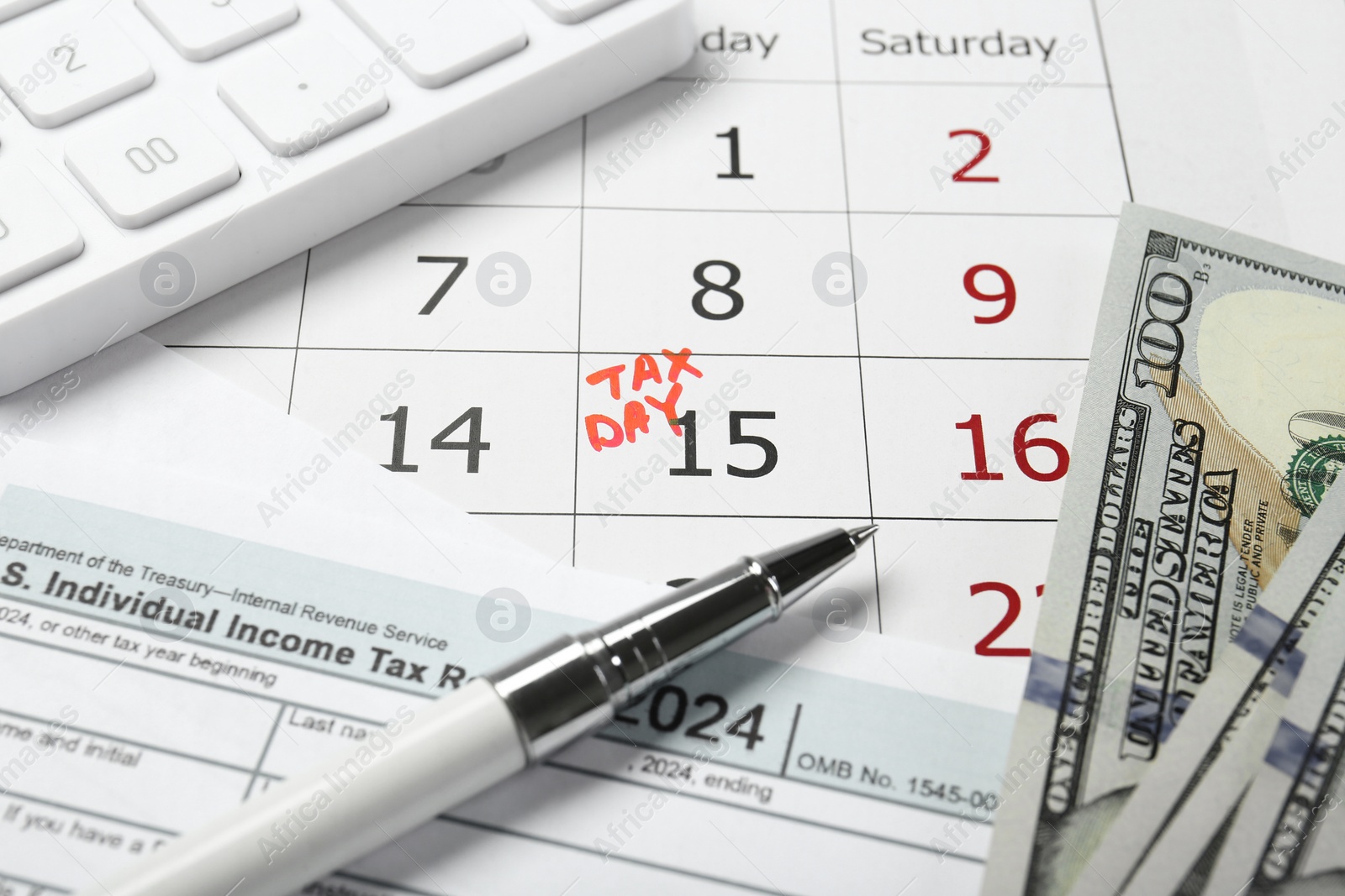 Photo of Calendar with date reminder about tax day, documents, pen, calculator and money, closeup