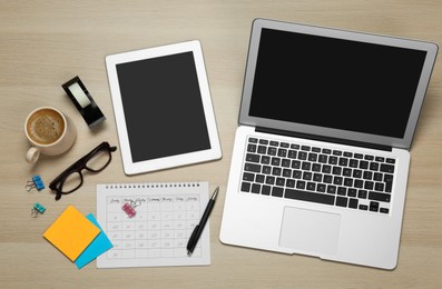 Photo of Modern gadgets, cup of coffee and office stationery on wooden table, flat lay. Distance learning