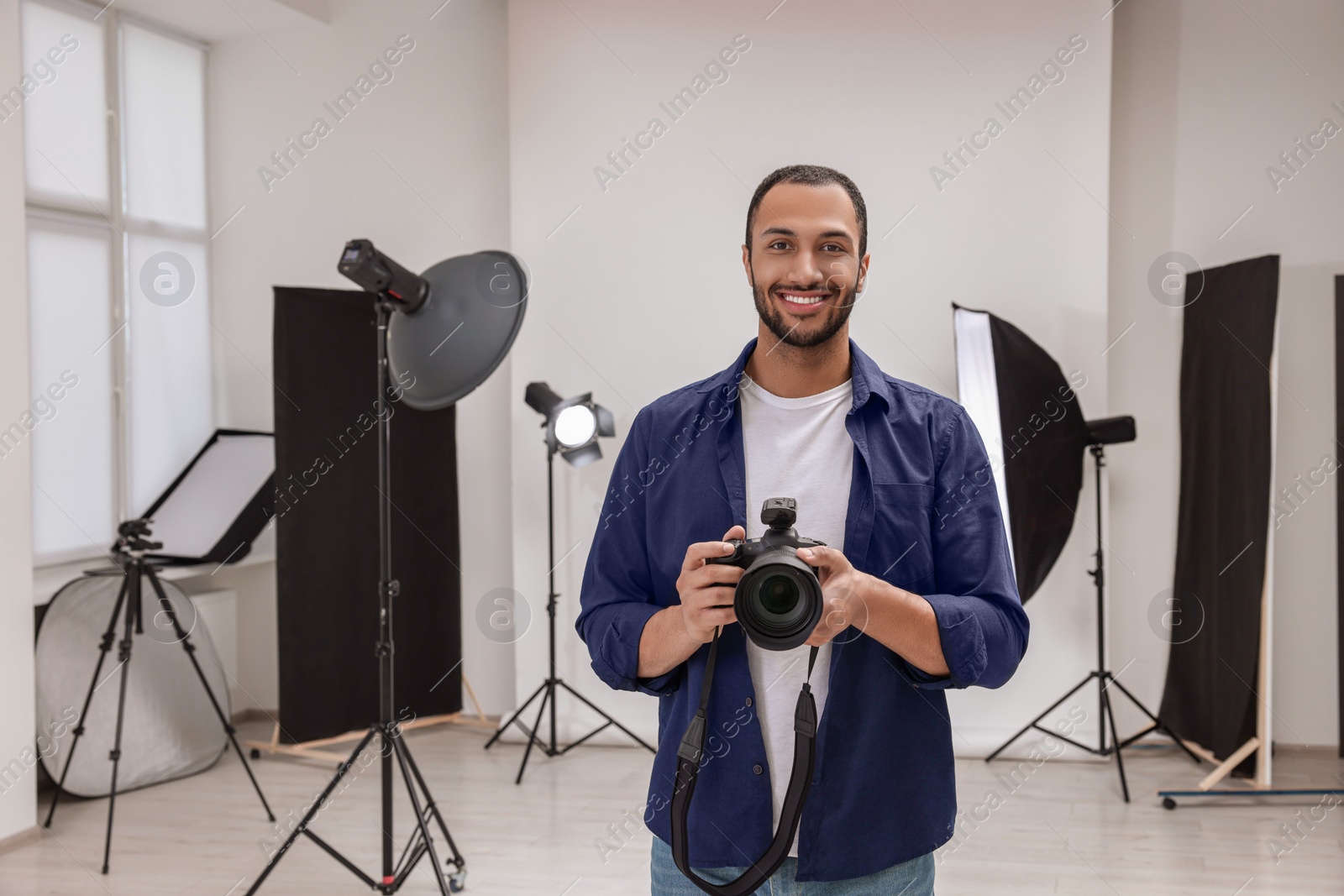 Photo of Young professional photographer with camera in modern photo studio, space for text