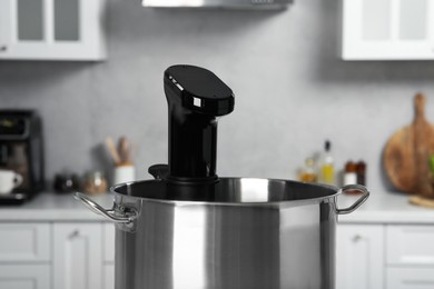 Photo of Pot with sous vide cooker in kitchen, closeup. Thermal immersion circulator