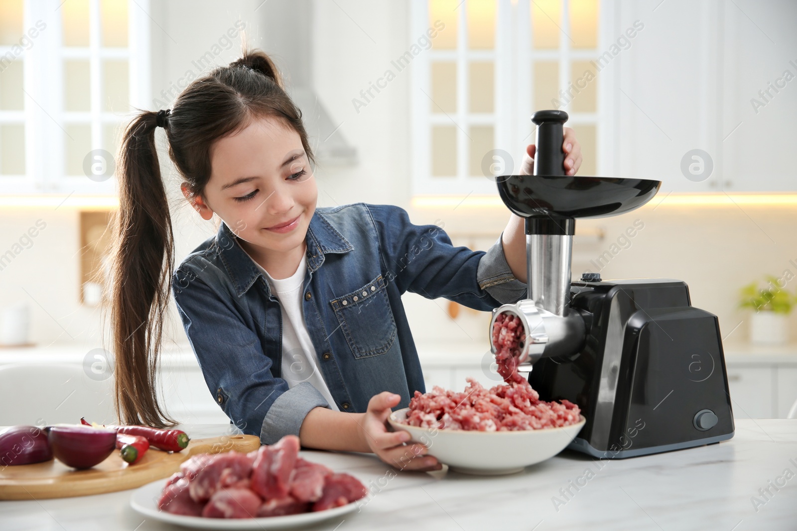 Photo of Little girl using modern meat grinder in kitchen