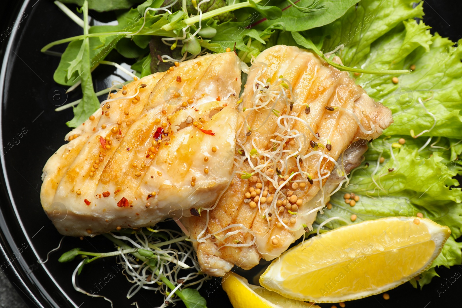 Photo of Tasty grilled fish with lemon on plate, closeup