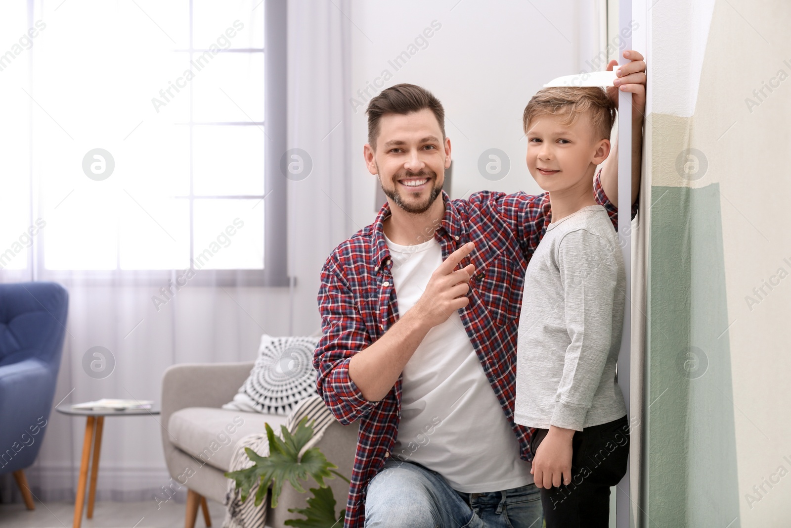 Photo of Young man measuring his son's height at home