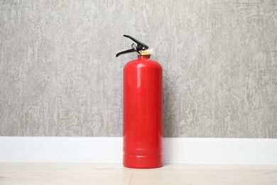 Photo of One fire extinguisher on floor near grey wall