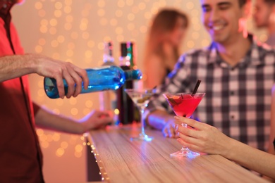 Young woman with glass of martini cocktail in bar, closeup