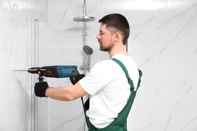 Photo of Handyman working with drill in bathroom. Professional construction tools