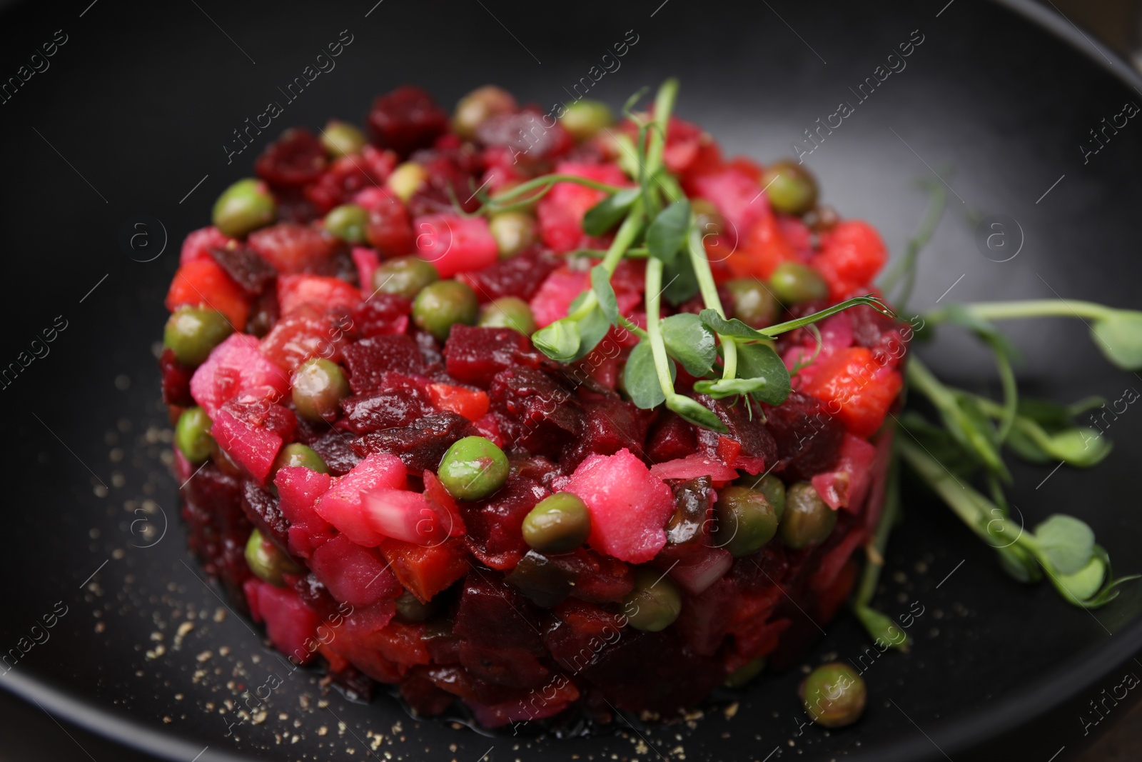 Photo of Delicious vinaigrette salad in black bowl, closeup