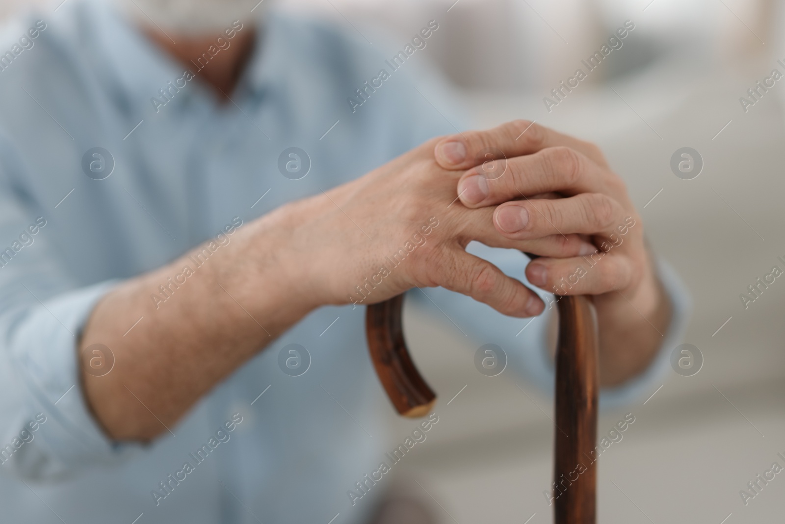 Photo of Grandpa with wooden walking cane indoors, closeup