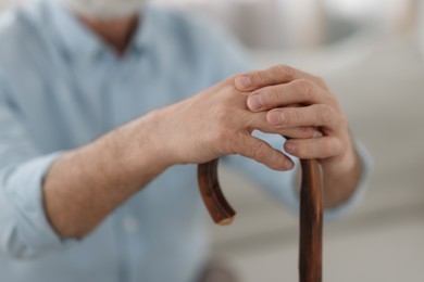 Grandpa with wooden walking cane indoors, closeup