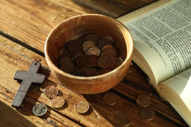 Donate and give concept. Bowl with coins, cross and Bible on wooden table