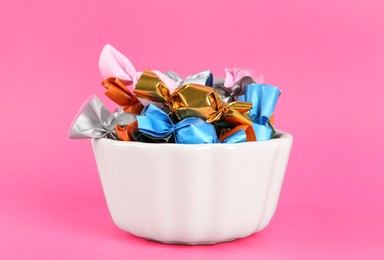 Photo of Candies in colorful wrappers on pink background, closeup