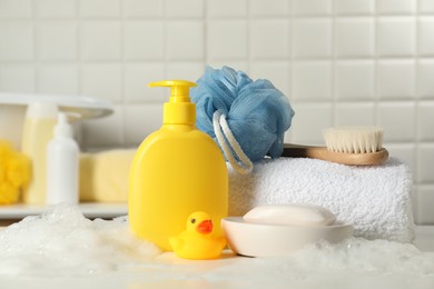 Photo of Baby cosmetic products, bath duck, brush and towel on white table