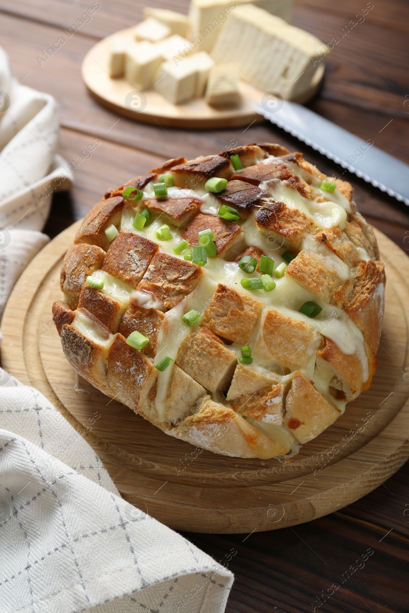 Photo of Freshly baked bread with tofu cheese and green onions on wooden table