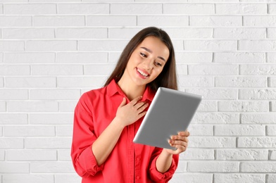 Woman using tablet for video chat against brick wall